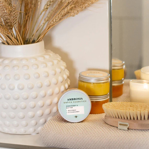 Bodybutter in Dose mit Vase und Getreide in natürlicher, häuslicher Umgebung.